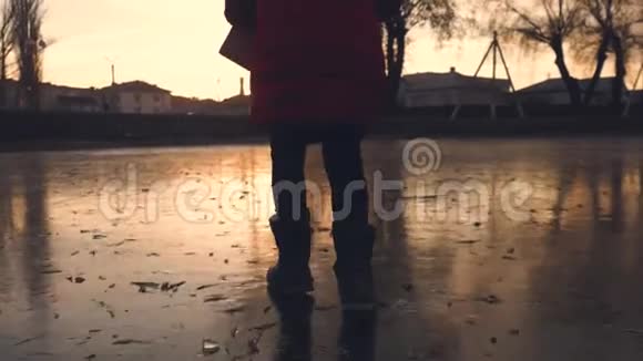 从一个女孩在冰冻的湖面上奔跑的镜头日落时分在下雪的冬天孩子们在户外跑步视频的预览图