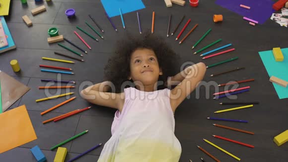 漂亮的非裔美国小女孩躺在地板上计划未来的假期视频的预览图