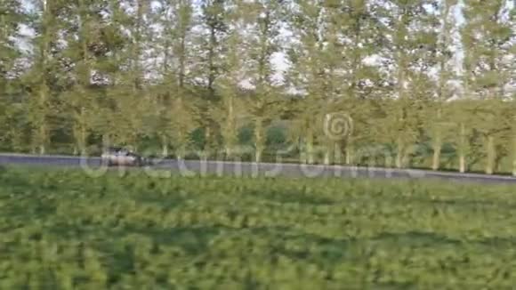 在乡间道路上行驶的灰色汽车的鸟瞰图侧视跟踪拍摄4K视频的预览图