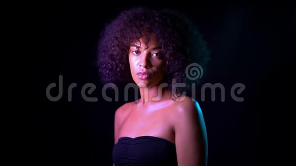 黑色背景下粉红色霓虹灯下年轻迷人的非洲裔美国女孩的肖像完美诱惑女人视频的预览图