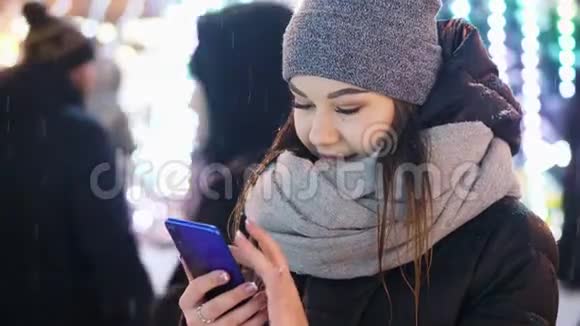 年轻女子在雪夜圣诞节和新年使用手机应用程序视频的预览图