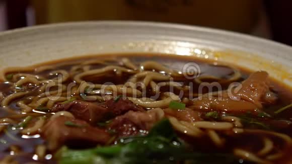 女人用棍子吃牛肉面的慢动作中式餐厅视频的预览图