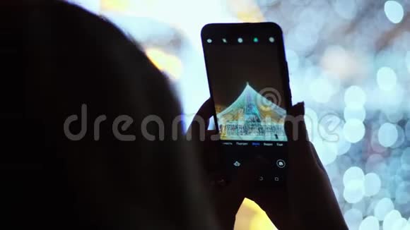女人在电话里拍照主城圣诞树庆祝新年视频的预览图