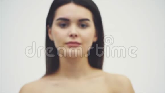 一个美丽的性感健康的女人站在白色背景下与蕨类植物摆姿势视频的预览图
