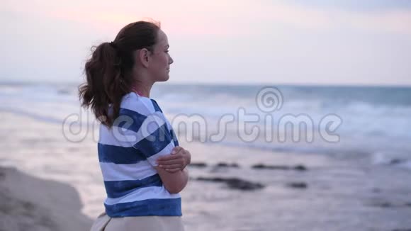 在海边看日落和海浪的年轻女子视频的预览图