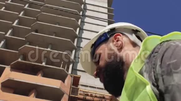 在建房屋背景下施工领班留胡子留胡子戴安全帽4k视频的预览图