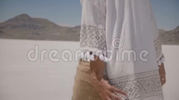 镜头跟随美丽快乐的女人在犹他州阳光明媚的盐漠湖享受阳光触摸头发和微笑视频的预览图