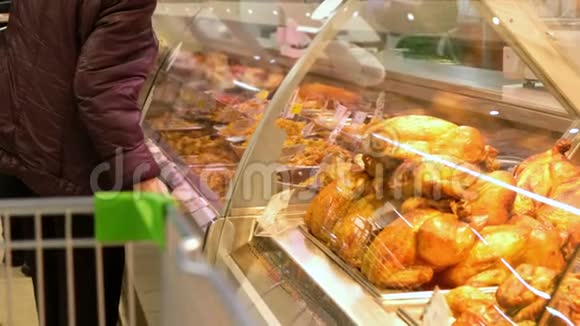 一位老年妇女在超市里挑选一只炸鸡人们购买食品零售食品工业视频的预览图