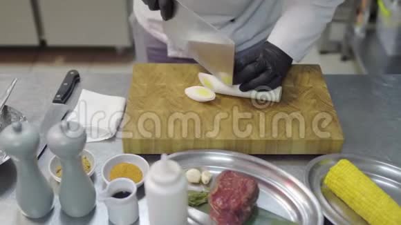 厨师手戴黑色乳胶手套在砧板上切柠檬草片带有厨房用具的厨房餐桌视频的预览图