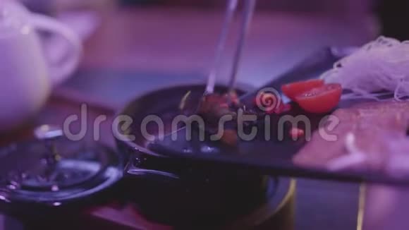 用蘑菇面条和番茄樱桃在一个黑色的碗里煮汤桌上有一个盖子视频的预览图