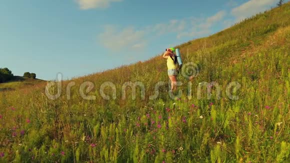 女徒步旅行者在山上背着一个背包透过望远镜看视频的预览图