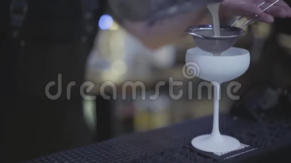 在令人惊叹的白色鸡尾酒杯中酒保的双手通过染色剂注入液体调酒师视频的预览图