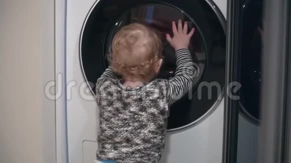 一岁男孩在家看洗衣机小男孩关上洗衣机视频的预览图