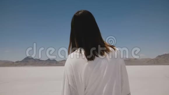 镜头跟随美丽的女人走在阳光明媚炎热的邦尼维尔盐沙漠湖中间穿着轻便的便服视频的预览图