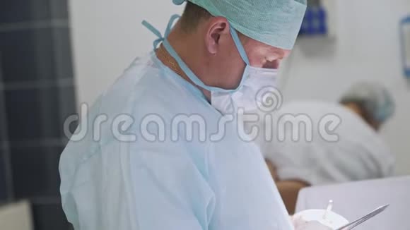手术期间穿无菌衣服和口罩的医生的侧视图手术室的外科医生视频的预览图