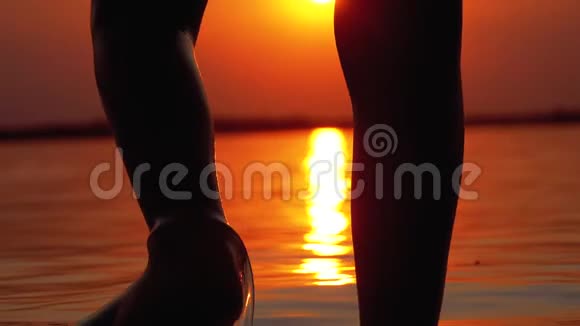 太阳落山时男孩奔跑入水的腿剪影并造成飞溅慢动作视频的预览图