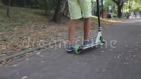 一个在公园里骑滑板车的脚男孩的特写镜头视频的预览图