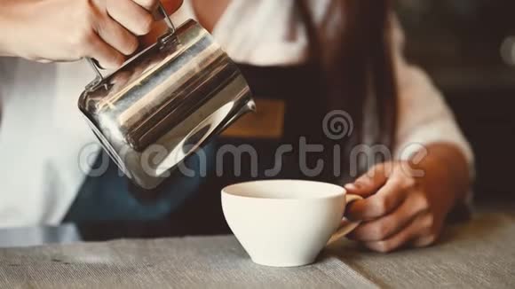 作为店主亚洲专业女咖啡师在自助餐厅的柜台酒吧里倒奶服务员视频的预览图