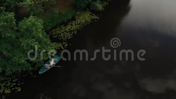 一对年轻男女在森林河上划着桨的船上漂浮天线视频的预览图