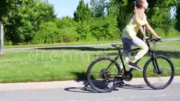运动的年轻女子骑自行车户外活跃的女人骑自行车在公园里视频的预览图