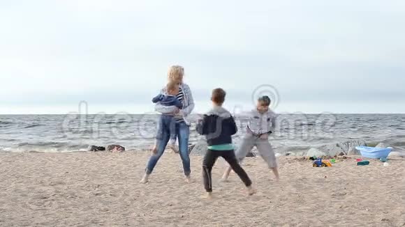 家庭度假在海洋一个年轻的女人有孩子跑来跑去玩耍和嬉戏视频的预览图