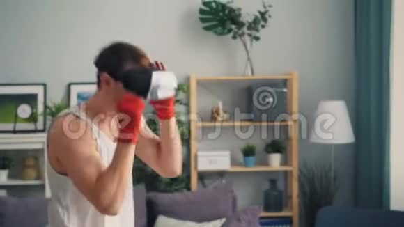 年轻男拳击手独自在家训练戴着虚拟现实眼镜视频的预览图