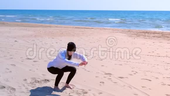 女子在海沙滩上做深蹲健身户外运动训练视频的预览图