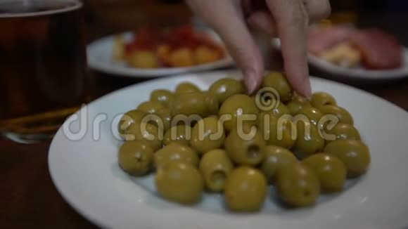4K闭上女人的手拿着一个绿色的橄榄在西班牙酒吧典型的绦虫视频的预览图
