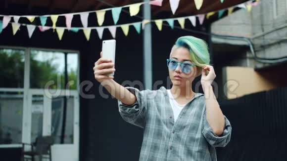 时尚的亚洲女孩太阳镜自拍与智能手机相机户外视频的预览图