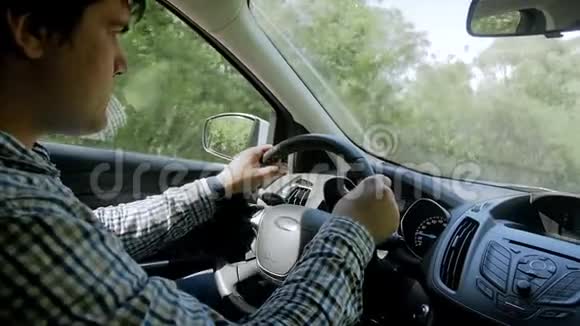 阳光明媚的乡村公路上穿衬衫开车的年轻人慢镜头视频的预览图