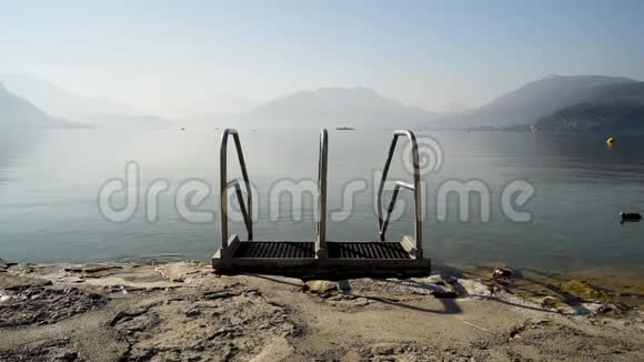 清晨法国阿尔卑斯山安纳西湖的海滩上有一个水池栏杆背景是雾和是雾和山视频的预览图