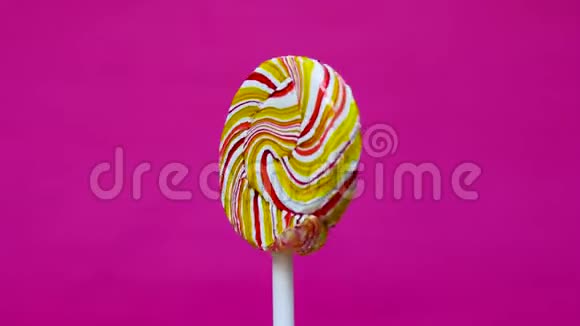 一根棍子上的水果糖果在明亮的粉红色背景上旋转快关门糖及其对人体健康的影响饮食和饮食视频的预览图