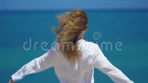 在美丽的海面上年轻女子的头发随风飘动双手举在悬崖之上概念自由视频的预览图