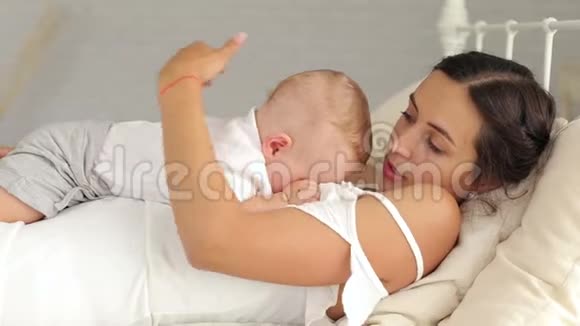 年轻的母亲抱着她新生的孩子女人和新出生的男孩放松视频的预览图