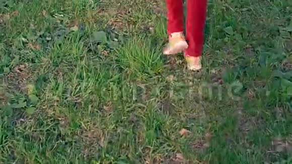 穿着红色牛仔裤和运动鞋的女孩的腿穿过草地视频的预览图