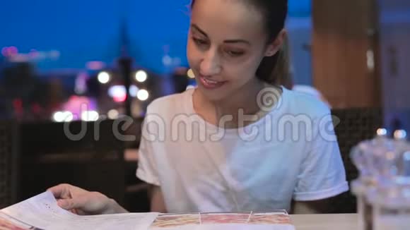 年轻的美女在餐厅看菜单翻页选择餐盘午餐约会视频的预览图