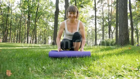 女健身教练在公园草地上展开瑜伽垫的慢动作视频做体育锻炼和运动视频的预览图