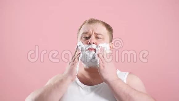 肥胖的男人穿着白色底衫胡须上有泡沫感到疼痛或刺激视频的预览图