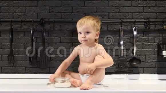 可爱的金发幼儿坐在厨房的桌子上用手指品尝糖4千克视频的预览图