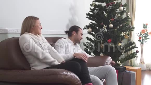 一个年轻人给他女朋友一份圣诞礼物漂亮的女孩对礼物感到惊喜和快乐爱情视频的预览图
