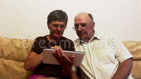 吸引人的成年女性和成年男性在平板电脑上查看照片视频的预览图