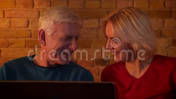 在舒适的公寓里坐在沙发上看电影的一对幸福的夫妇的特写镜头视频的预览图