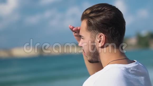 站在大海上的英俊的年轻人看着水用手遮住眼睛白胡子男视频的预览图