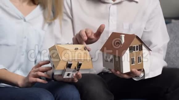 在男人和女人的手中关闭两个房子的3D模型视频的预览图