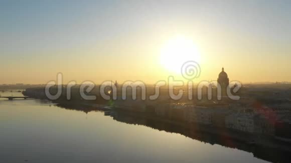 日出时飞越圣彼得堡和涅瓦河在地平线上飞过圣以萨克大教堂视频的预览图