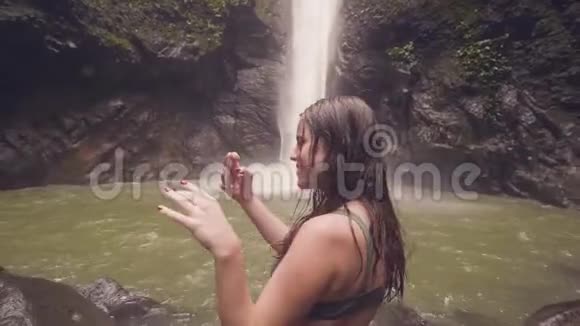 微笑的女人拍摄热带瀑布到雨林手机的全景照片旅行博客写手在做视频的预览图