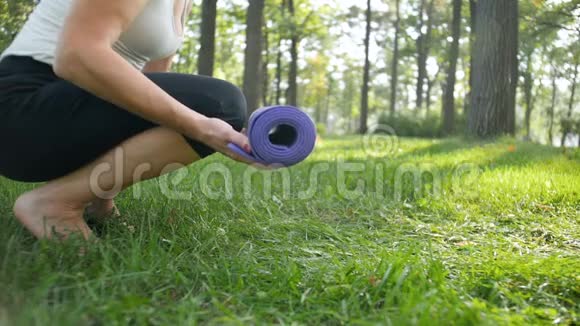 女子在公园展开和投掷健身垫的慢速特写视频视频的预览图