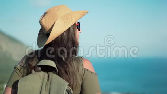 微笑成功的背包客女人欣赏山顶上令人惊叹的海景视频的预览图