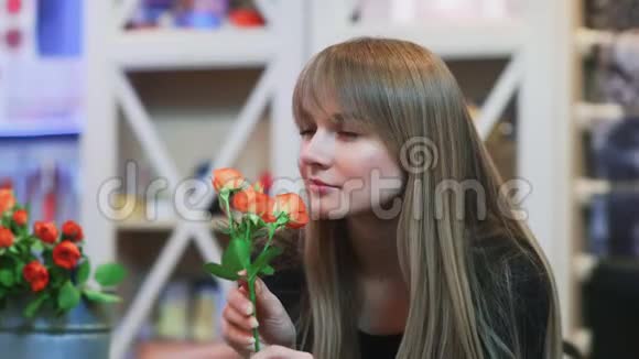 一个年轻的女人在商店闻一朵花视频的预览图