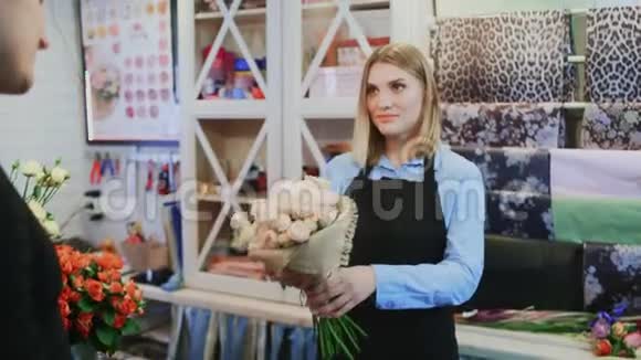 女孩花店正在卖花束给商店的男花店老板视频的预览图